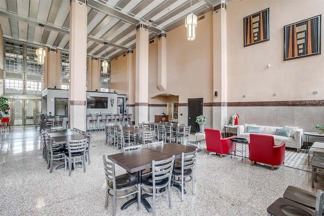 dining area with beam ceiling and a high ceiling