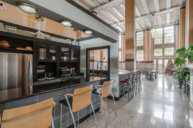 bar featuring a towering ceiling and stainless steel appliances