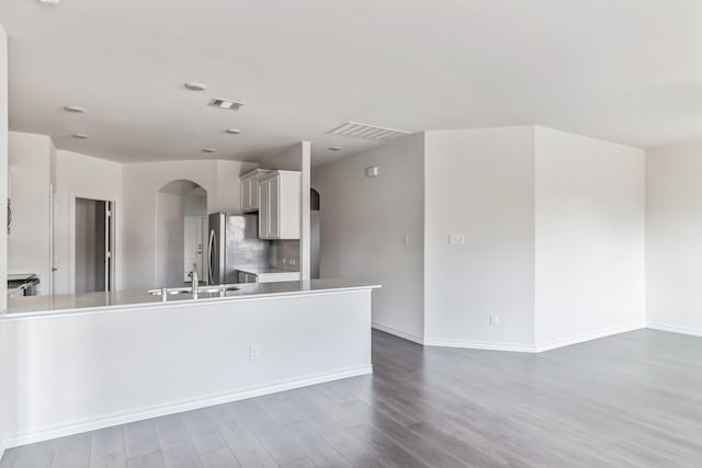 kitchen with white cabinets, hardwood / wood-style floors, stainless steel fridge, and sink