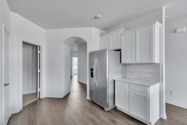 kitchen featuring light hardwood / wood-style flooring, stainless steel fridge, a textured ceiling, decorative backsplash, and white cabinets