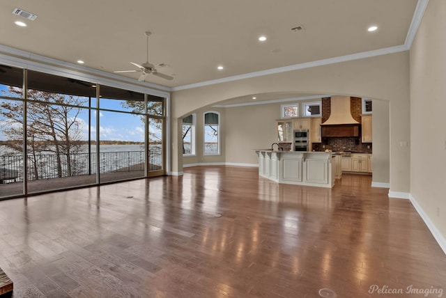 living room featuring a water view, sink, crown molding, hardwood / wood-style flooring, and ceiling fan