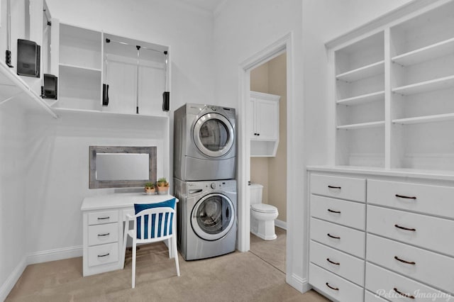 laundry room with light carpet, cabinets, and stacked washer and clothes dryer