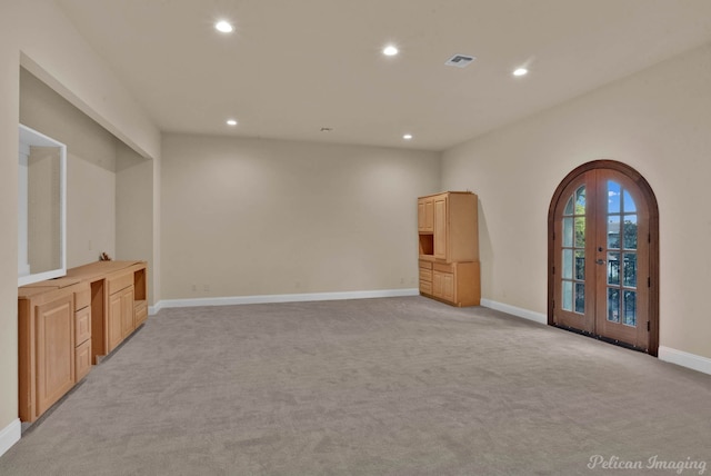 unfurnished living room featuring light carpet and french doors