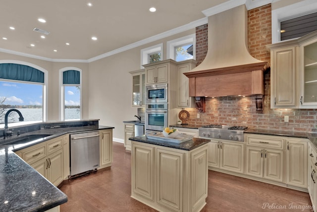 kitchen featuring premium range hood, cream cabinets, sink, a kitchen island, and stainless steel appliances