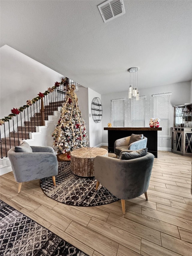 living room with light hardwood / wood-style floors, a textured ceiling, and an inviting chandelier