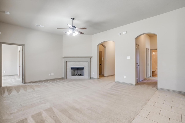 unfurnished living room featuring ceiling fan, light colored carpet, and a tile fireplace