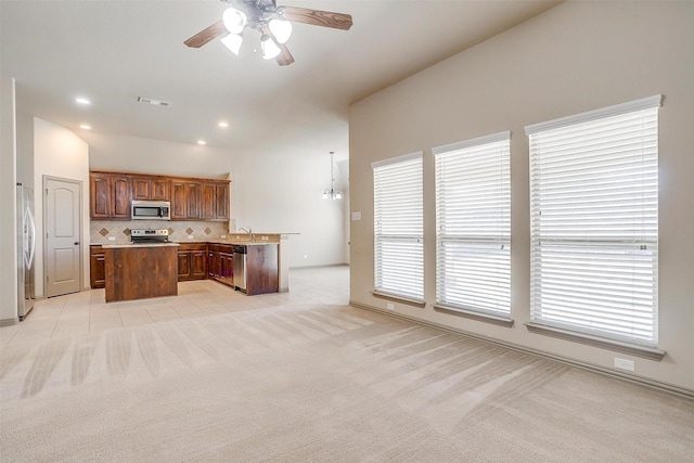 kitchen with ceiling fan with notable chandelier, light colored carpet, decorative light fixtures, and appliances with stainless steel finishes