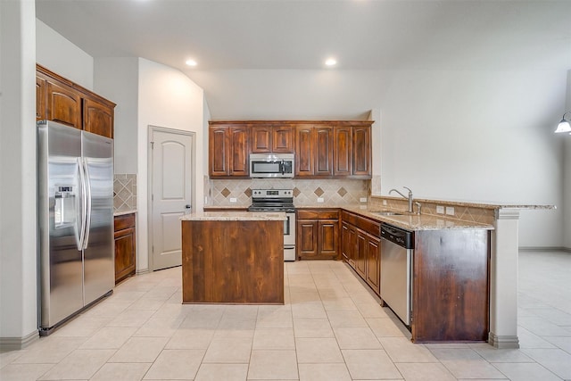 kitchen featuring sink, stainless steel appliances, light tile patterned floors, kitchen peninsula, and a kitchen island