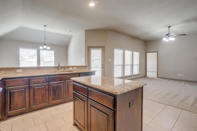 kitchen featuring sink, a center island, hanging light fixtures, light carpet, and ceiling fan with notable chandelier