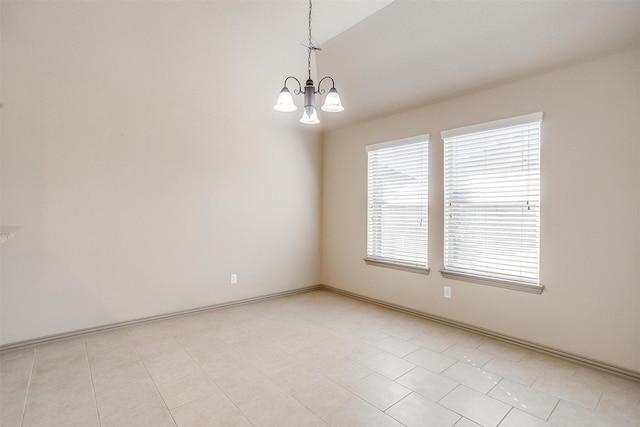 empty room with plenty of natural light, light tile patterned floors, and an inviting chandelier