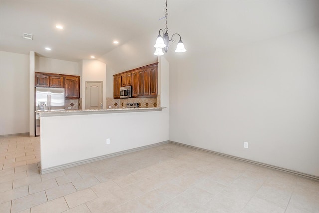 kitchen featuring appliances with stainless steel finishes, tasteful backsplash, vaulted ceiling, a notable chandelier, and light tile patterned flooring