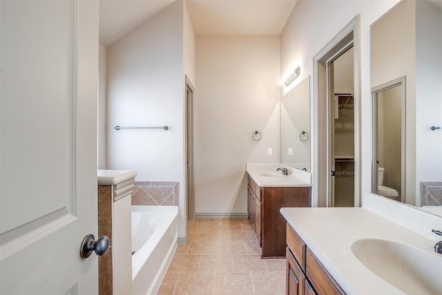 bathroom with tile patterned floors, vanity, a bathtub, and toilet