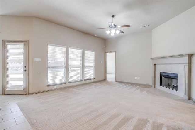 unfurnished living room with ceiling fan, light colored carpet, and a tiled fireplace