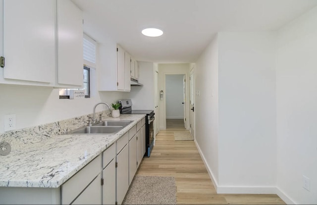 kitchen with stainless steel electric range oven, sink, white cabinets, and light hardwood / wood-style floors