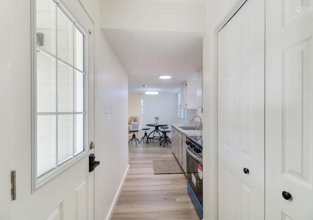 interior space featuring white cabinets, black electric range oven, light hardwood / wood-style floors, and sink