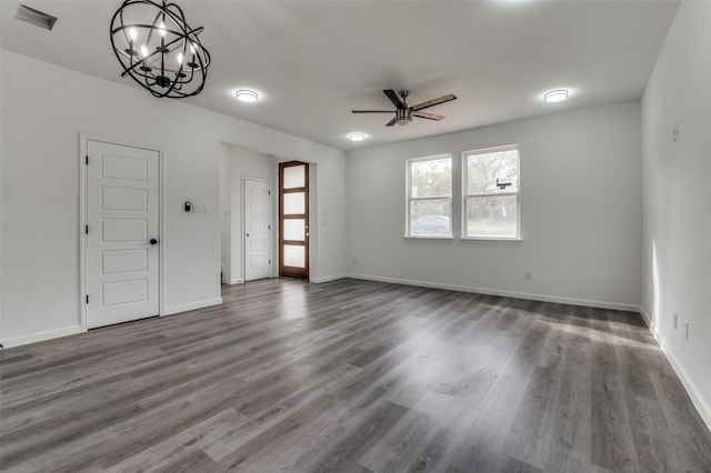 unfurnished living room featuring dark hardwood / wood-style floors and ceiling fan with notable chandelier