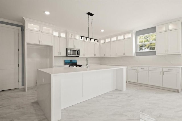 kitchen with an island with sink, white cabinetry, stainless steel appliances, and light countertops