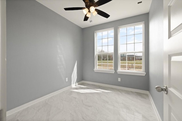 spare room with ceiling fan and baseboards