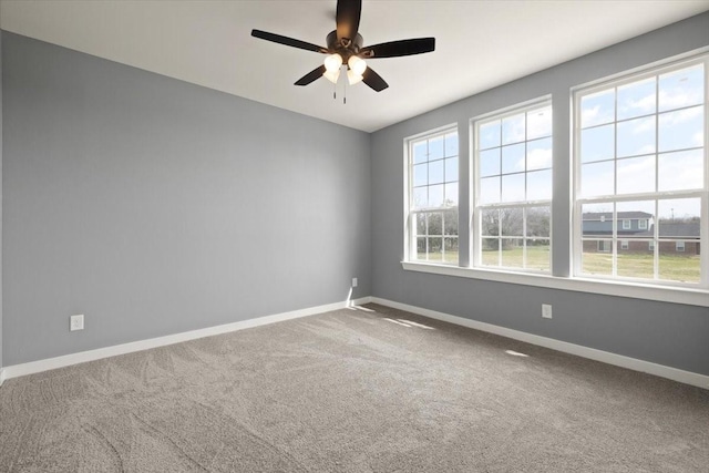 carpeted spare room with a ceiling fan and baseboards