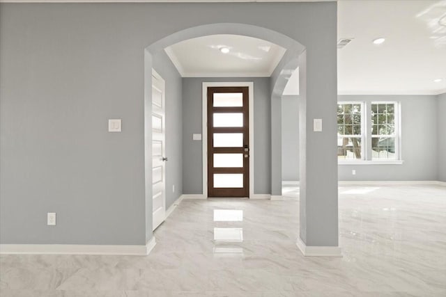 entryway featuring arched walkways, marble finish floor, visible vents, ornamental molding, and baseboards