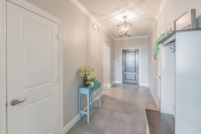 entryway with crown molding, light tile patterned floors, and an inviting chandelier