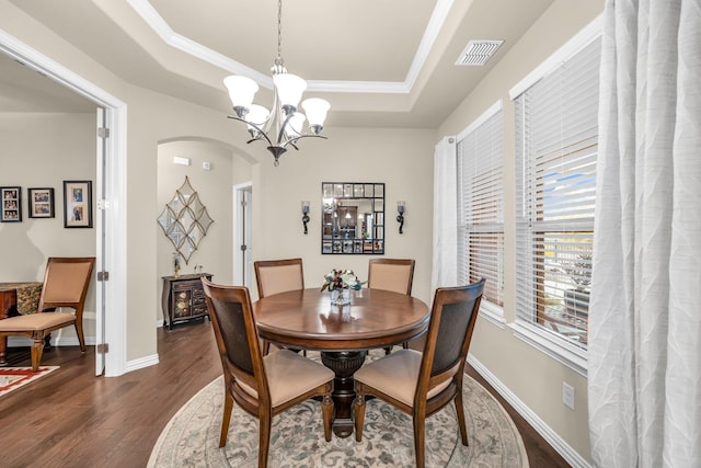 dining area featuring a tray ceiling, a chandelier, dark hardwood / wood-style floors, and ornamental molding