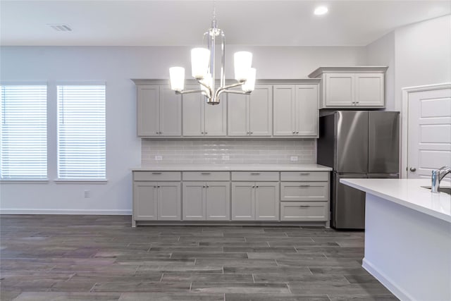 kitchen featuring pendant lighting, dark hardwood / wood-style floors, gray cabinets, stainless steel fridge, and tasteful backsplash