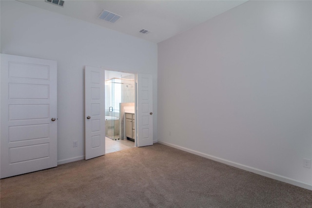 unfurnished bedroom featuring ensuite bathroom and light carpet