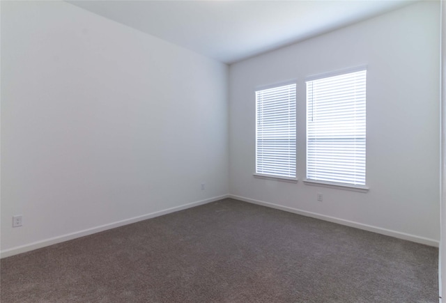 empty room with dark carpet and a wealth of natural light