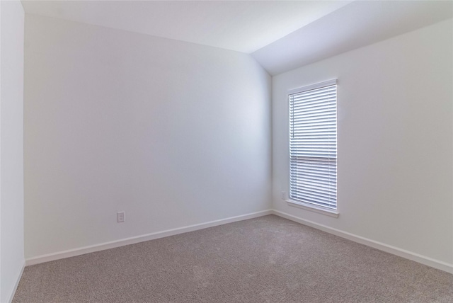 empty room featuring lofted ceiling and carpet flooring