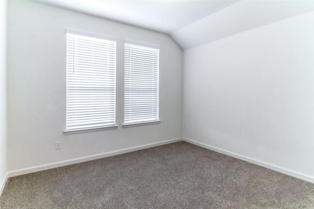 spare room with carpet flooring and vaulted ceiling