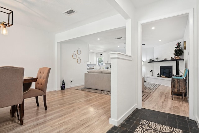 dining room with wood-type flooring and a brick fireplace