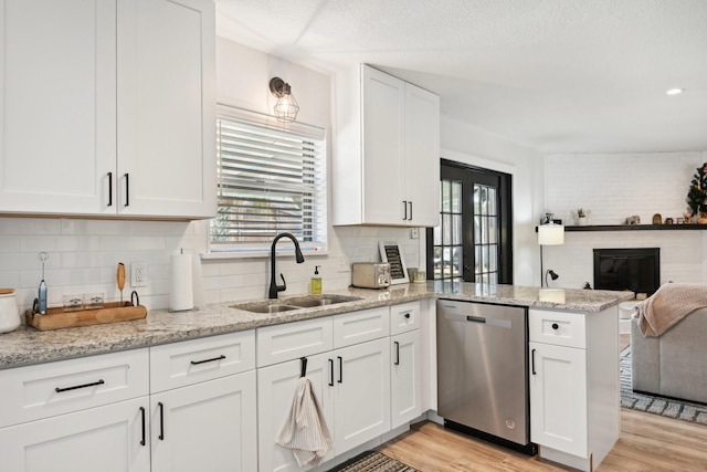 kitchen featuring sink, white cabinetry, light wood-type flooring, stainless steel dishwasher, and kitchen peninsula