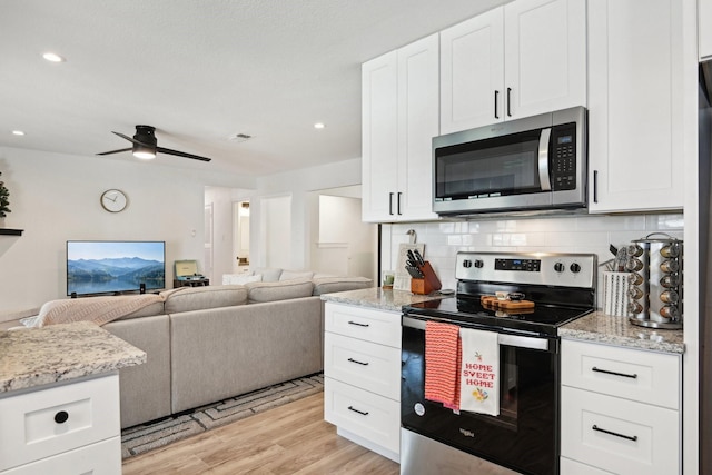 kitchen featuring stainless steel appliances, white cabinetry, light stone countertops, and decorative backsplash