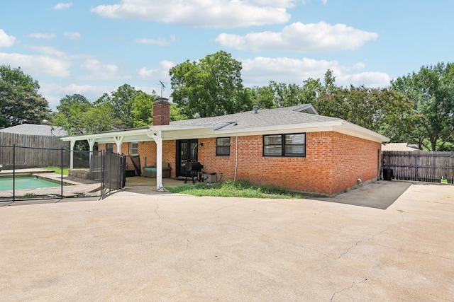 rear view of property featuring a fenced in pool and a patio area