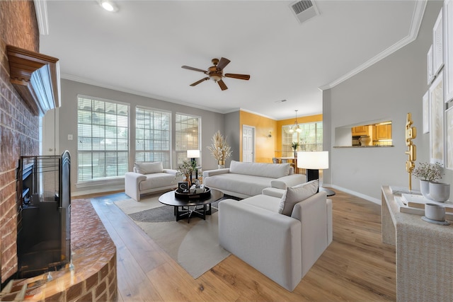 living room featuring a brick fireplace, crown molding, ceiling fan, and light wood-type flooring