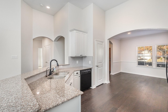 kitchen with dark hardwood / wood-style flooring, light stone counters, sink, white cabinets, and black dishwasher