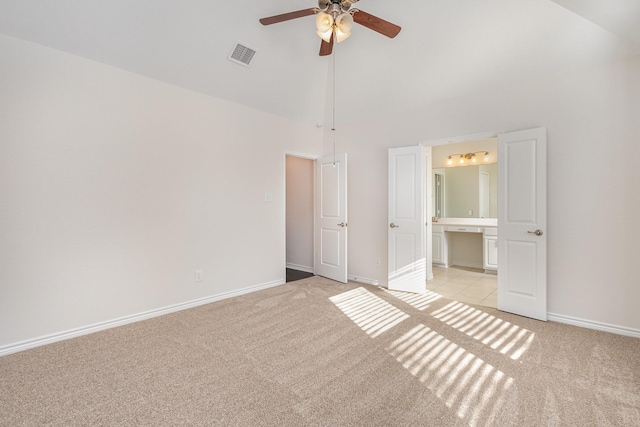 unfurnished bedroom with ceiling fan, light colored carpet, ensuite bathroom, and high vaulted ceiling