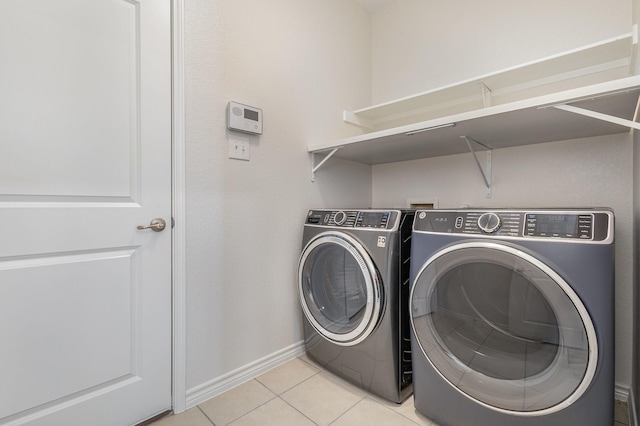 clothes washing area featuring light tile patterned floors and washer and dryer