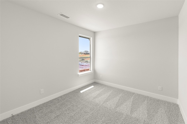 spare room with carpet, visible vents, and baseboards