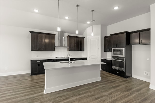 kitchen featuring stainless steel appliances, light countertops, wall chimney range hood, a sink, and baseboards