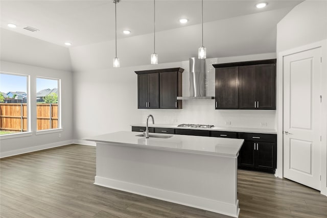 kitchen with stainless steel gas stovetop, dark wood-style floors, vaulted ceiling, wall chimney exhaust hood, and backsplash