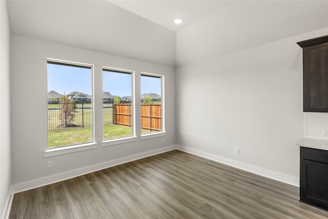 unfurnished dining area featuring baseboards, wood finished floors, and vaulted ceiling