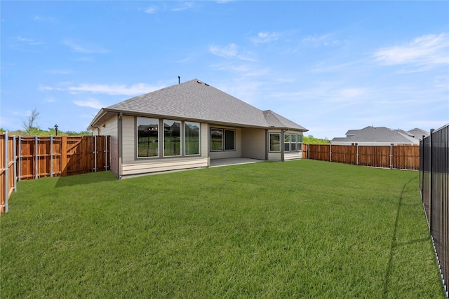 back of house with a lawn, roof with shingles, a patio area, and a fenced backyard