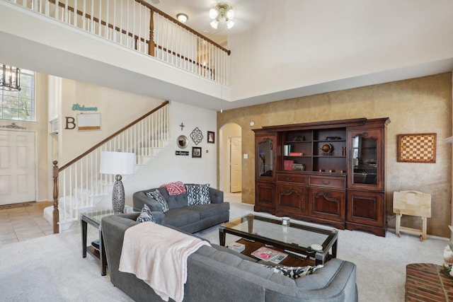 living room with a towering ceiling and light colored carpet