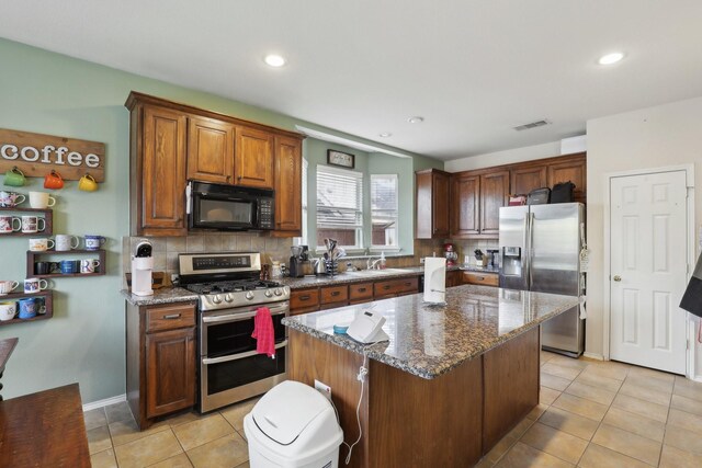 kitchen featuring dark stone counters, sink, decorative backsplash, appliances with stainless steel finishes, and a kitchen island