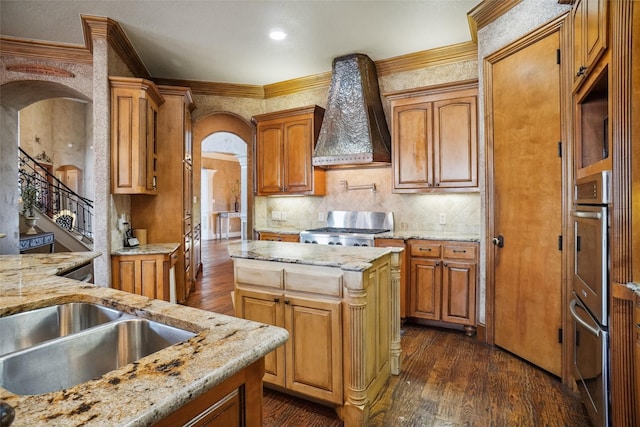 kitchen with a kitchen island, dark hardwood / wood-style floors, range, light stone counters, and custom range hood