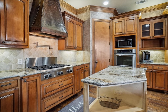 kitchen with premium range hood, appliances with stainless steel finishes, dark hardwood / wood-style flooring, and light stone countertops