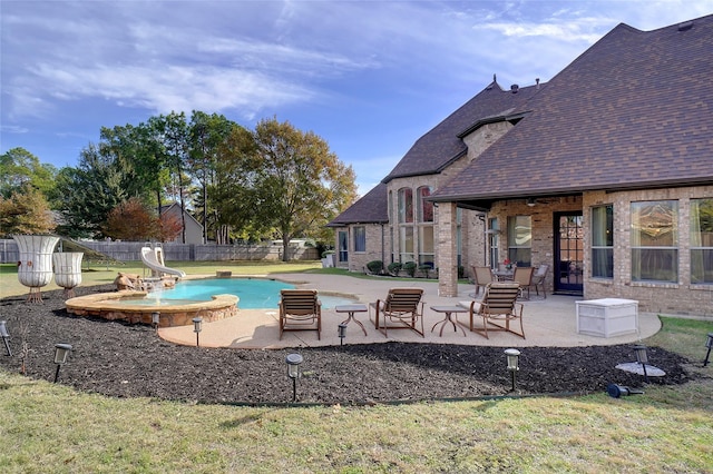 view of pool with a water slide, a yard, and a patio area