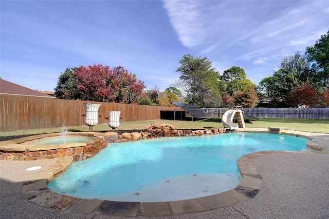 view of pool with a yard, an in ground hot tub, and a water slide